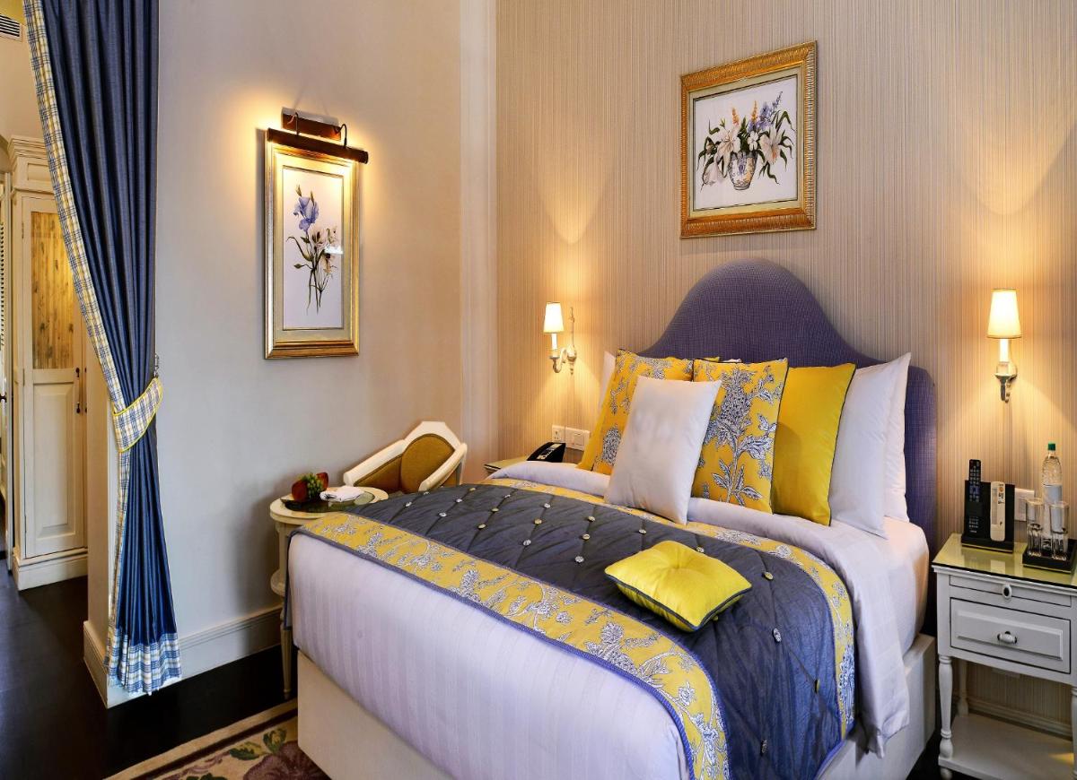 a bedroom with a large bed with blue and yellow pillows at Welcomhotel by ITC Hotels, The Savoy, Mussoorie in Mussoorie
