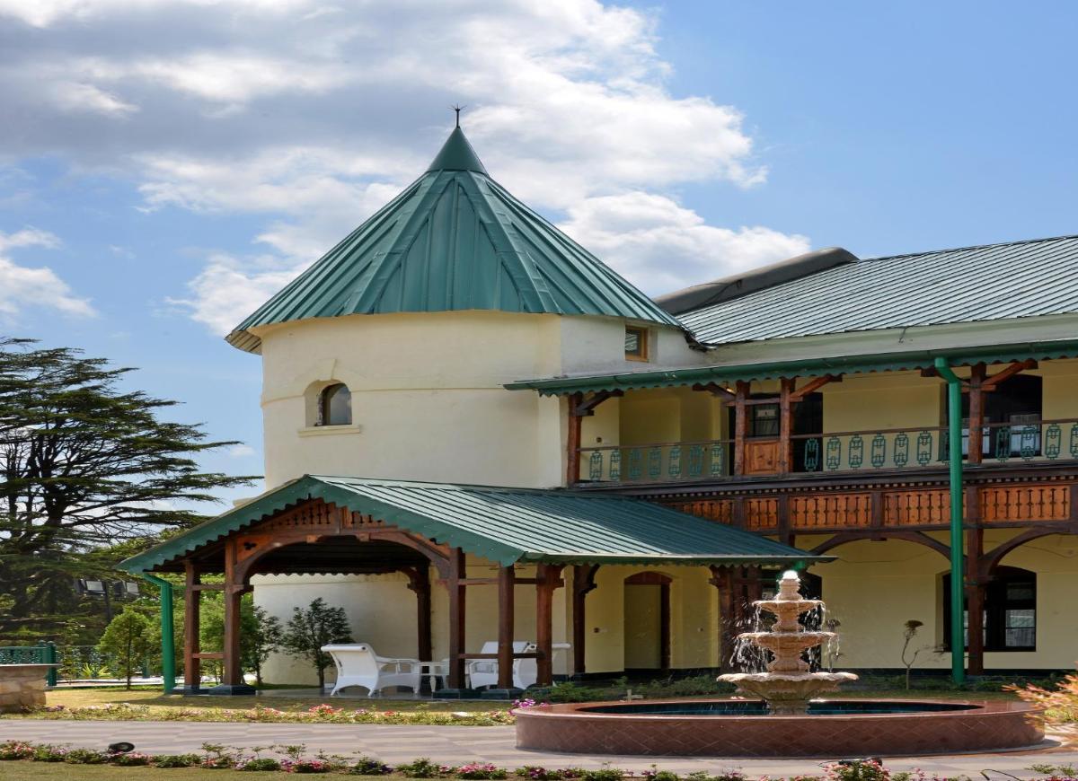 a large building with a green roof with a fountain at Welcomhotel by ITC Hotels, The Savoy, Mussoorie in Mussoorie