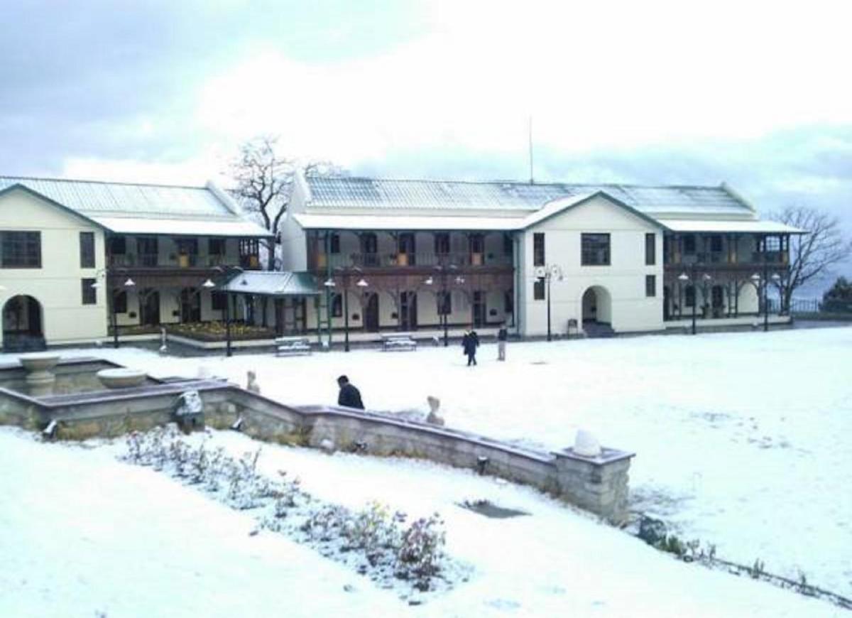 a building covered in snow with people walking around it at Welcomhotel by ITC Hotels, The Savoy, Mussoorie in Mussoorie