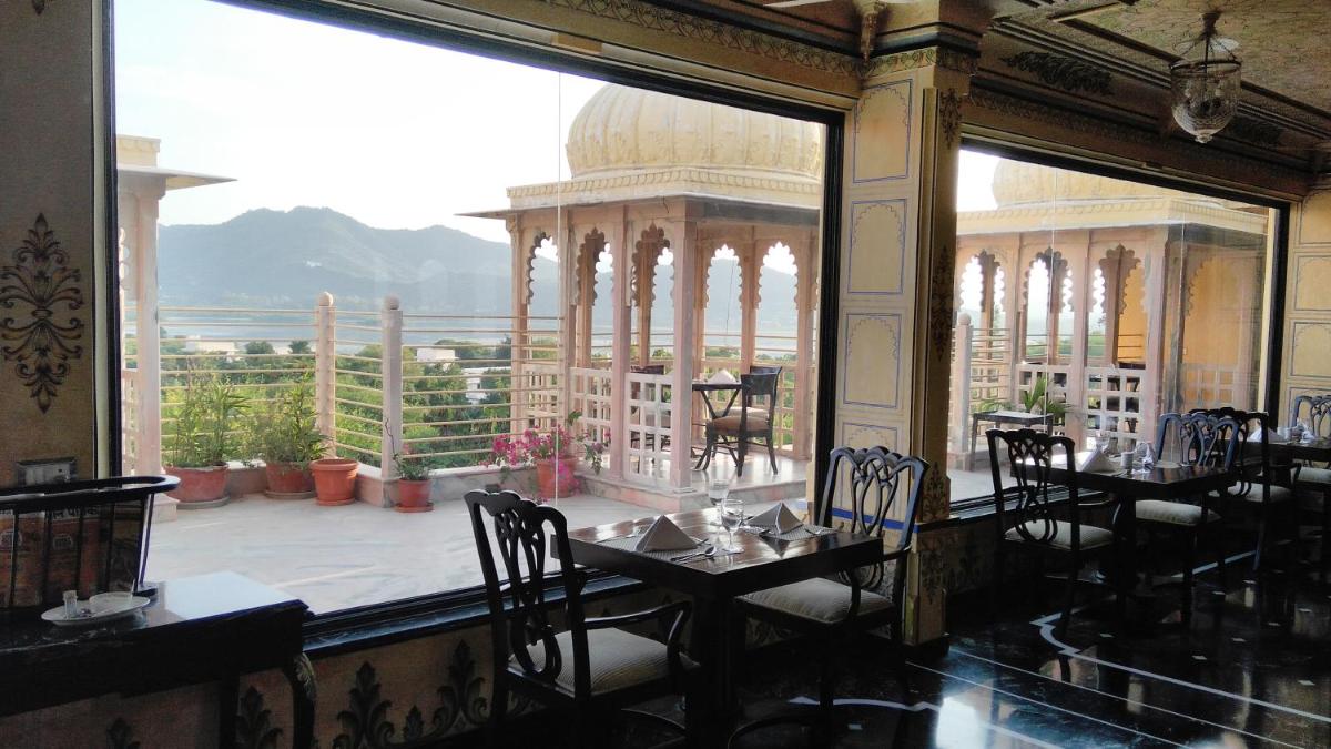 a restaurant with a view of a balcony with tables and chairs at Chunda Palace in Udaipur