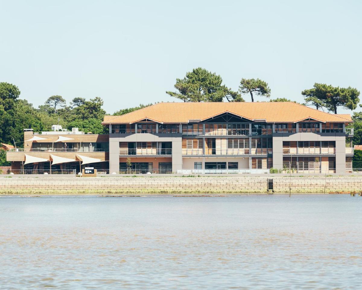 un grand bâtiment à côté d'un plan d'eau dans l'établissement Hôtel & Spa Villa Seren, à Hossegor