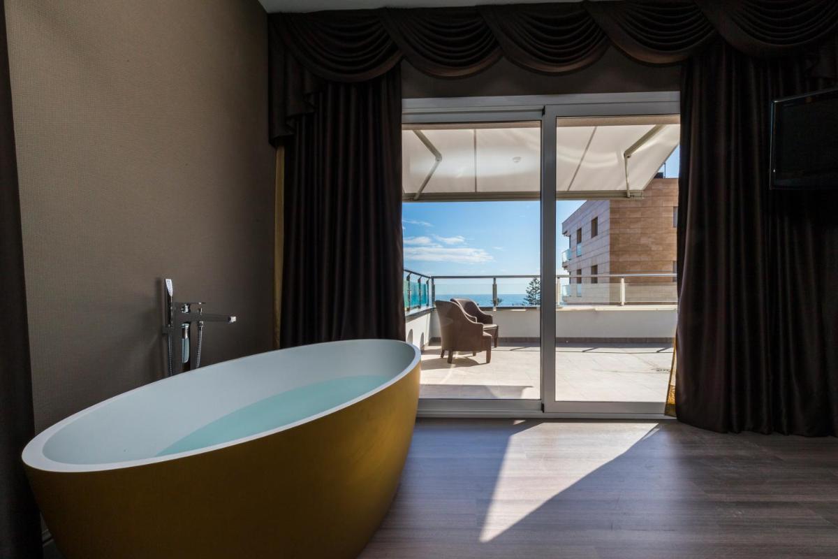 Baño con bañera frente a una ventana en Sant Jordi Boutique Hotel, en Calella