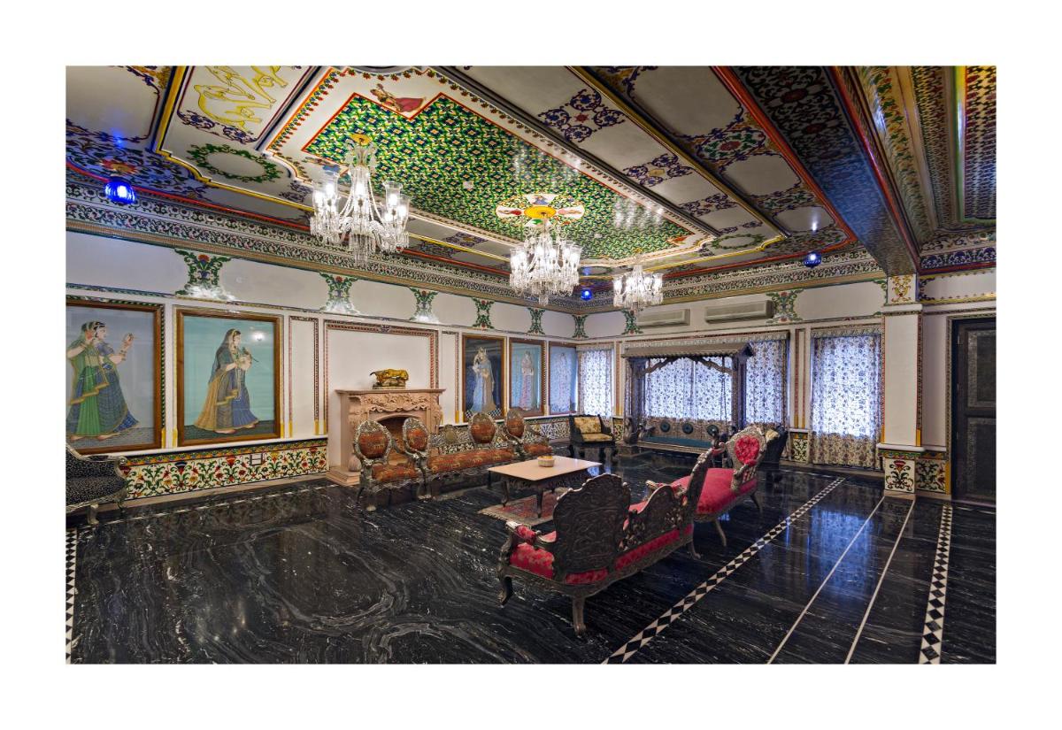 a living room with a chandelier and paintings on the ceilings at Chunda Palace in Udaipur