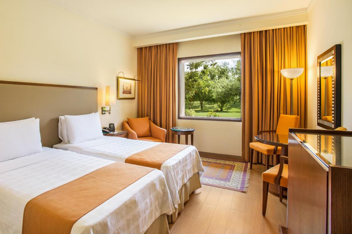 a hotel room with two beds and a window at Trident Agra in Agra