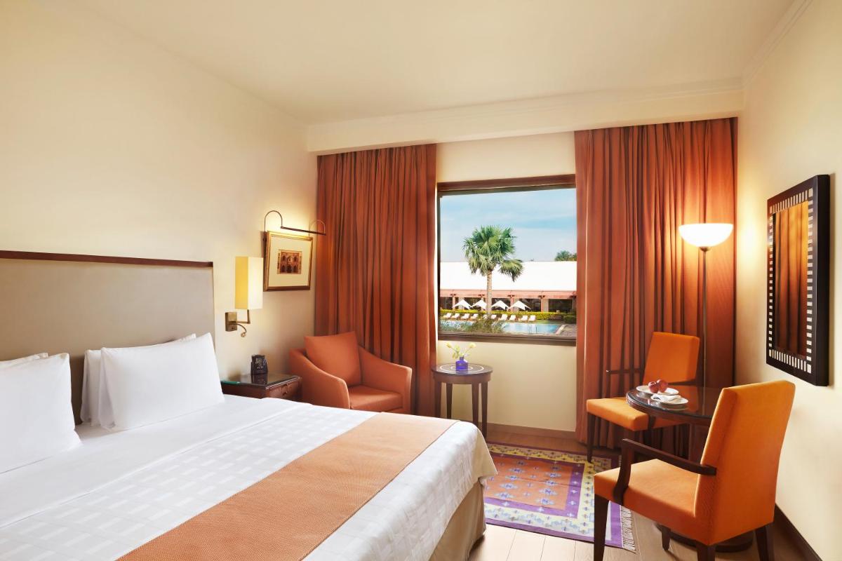 a hotel room with a bed and a large window at Trident Agra in Agra