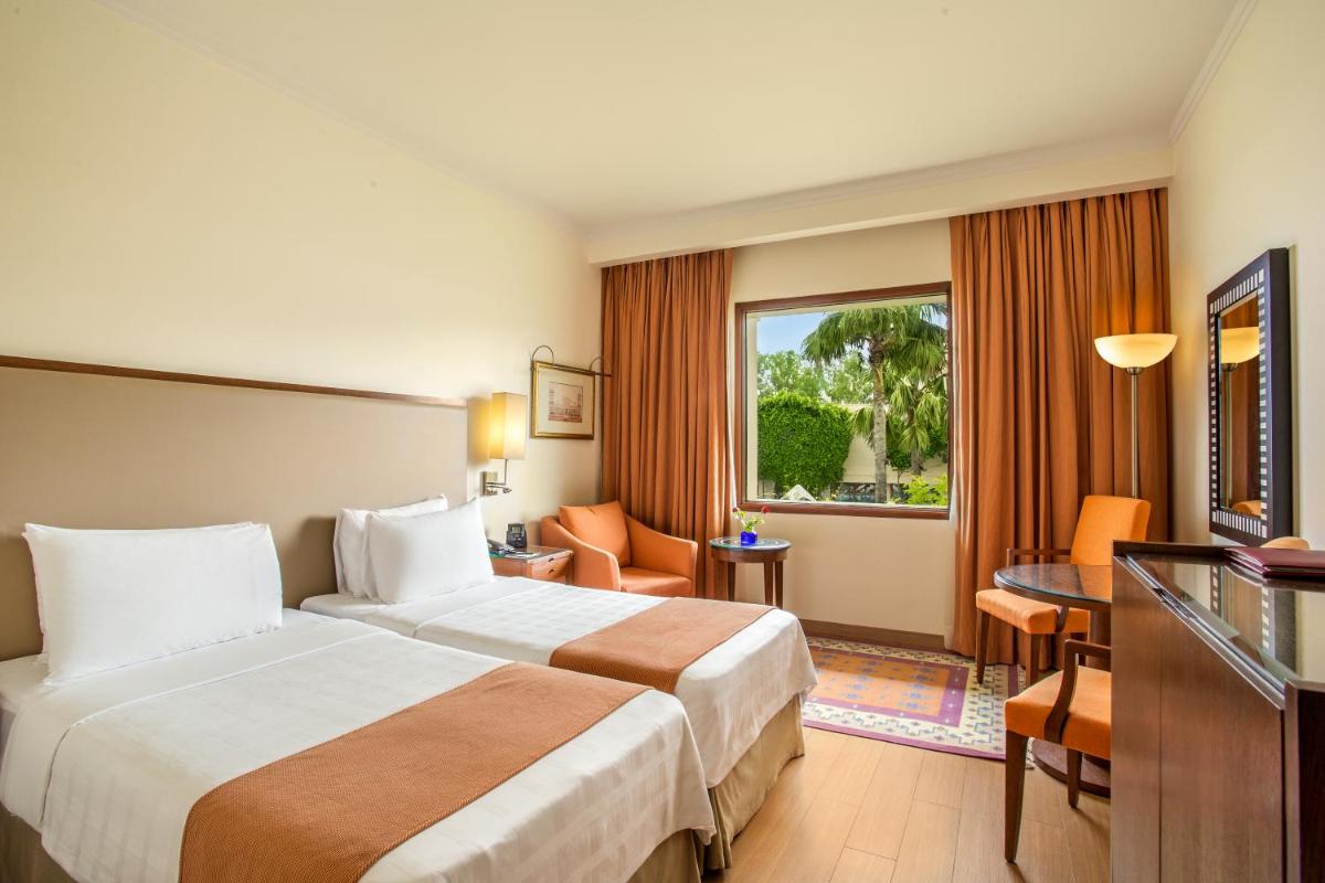 a hotel room with two beds and a television at Trident Agra in Agra