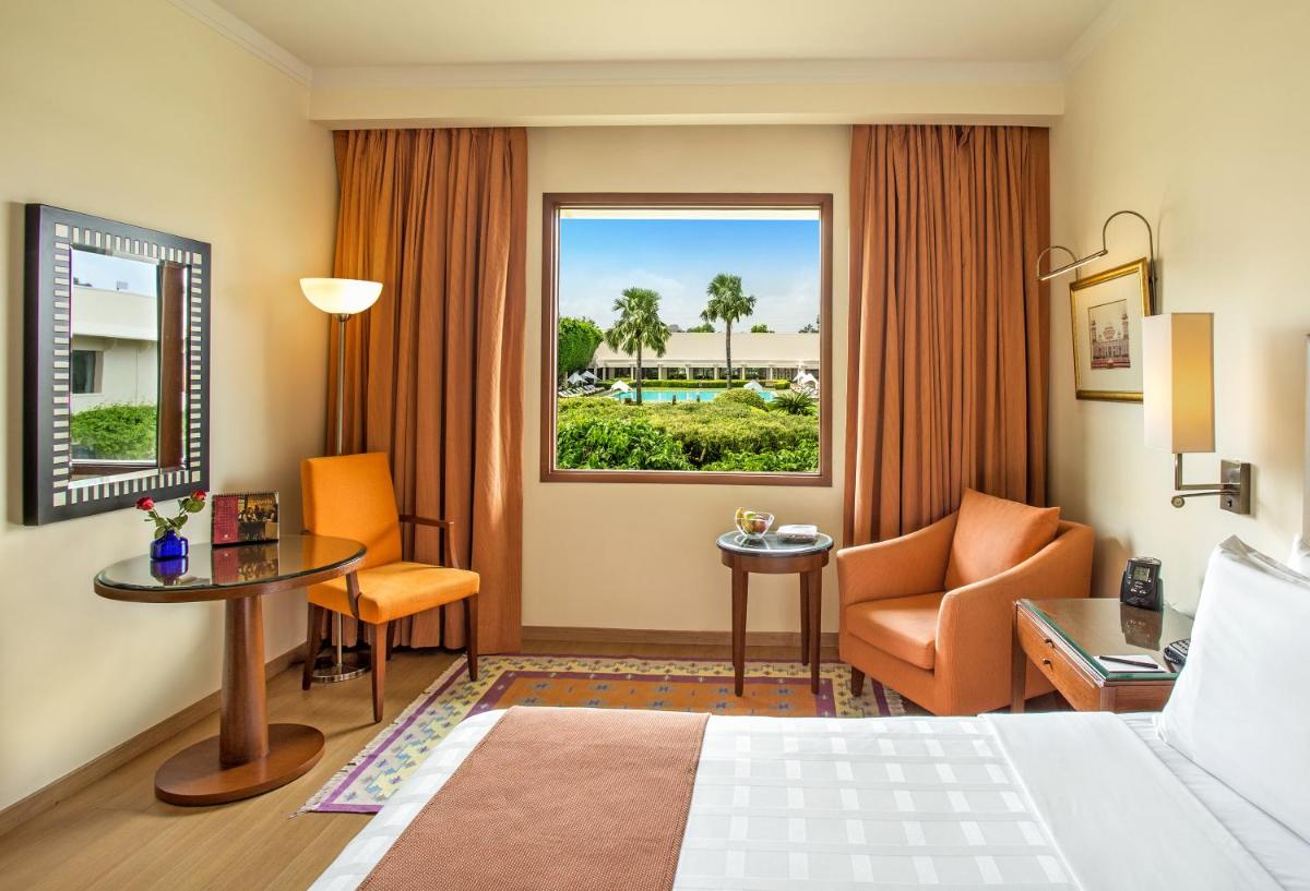 a hotel room with a bed and a desk and a window at Trident Agra in Agra