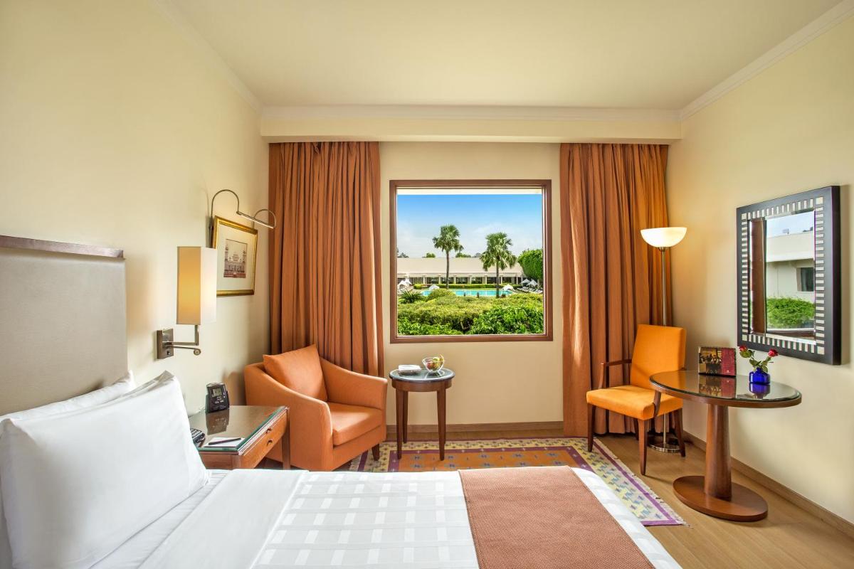 a hotel room with a bed and a chair and a window at Trident Agra in Agra