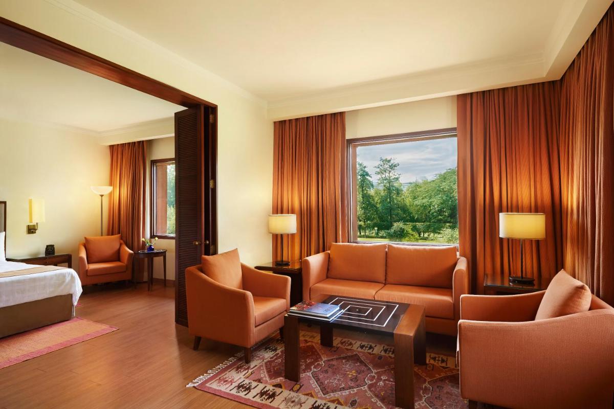 a hotel room with a bed and a living room at Trident Agra in Agra