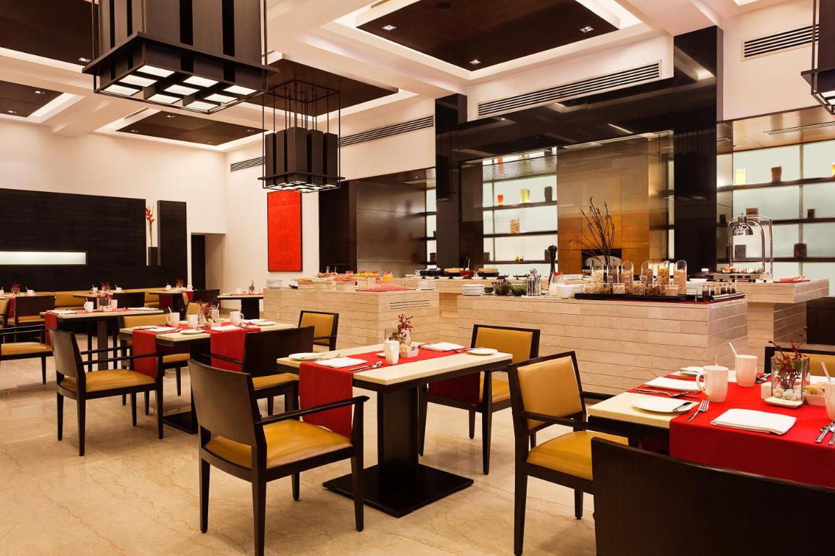 a restaurant with tables and chairs and a kitchen at Trident Agra in Agra