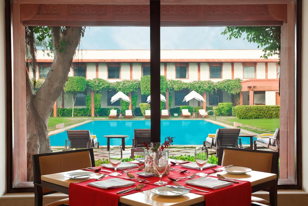 a table with red table cloths on it next to a pool at Trident Agra in Agra