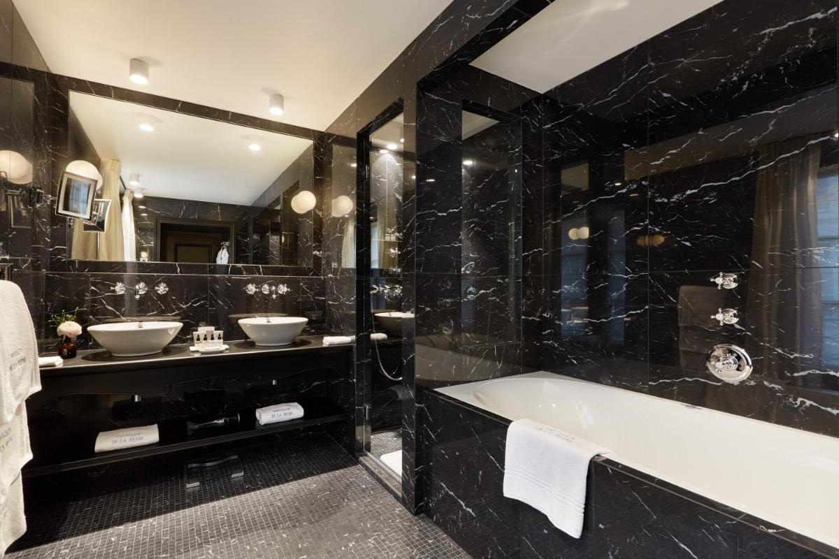 - une salle de bains noire avec deux lavabos et une baignoire dans l'établissement Le Pavillon de la Reine & Spa, Place des Vosges, à Paris