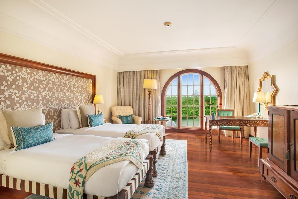 a hotel room with two beds and a desk at The Oberoi Amarvilas Agra in Agra