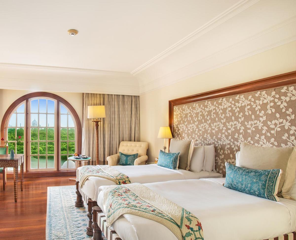 a hotel room with three beds and a window at The Oberoi Amarvilas Agra in Agra