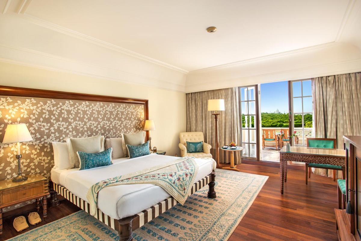 a bedroom with a bed and a desk and a balcony at The Oberoi Amarvilas Agra in Agra