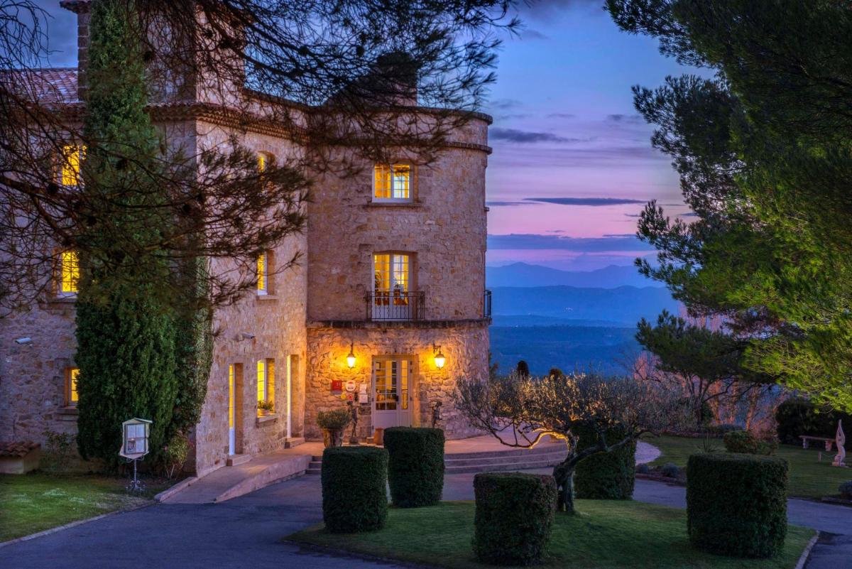 Un grand bâtiment en pierre avec des lumières allumées dans l'établissement La Bastide De Tourtour Hotel & Spa, à Tourtour