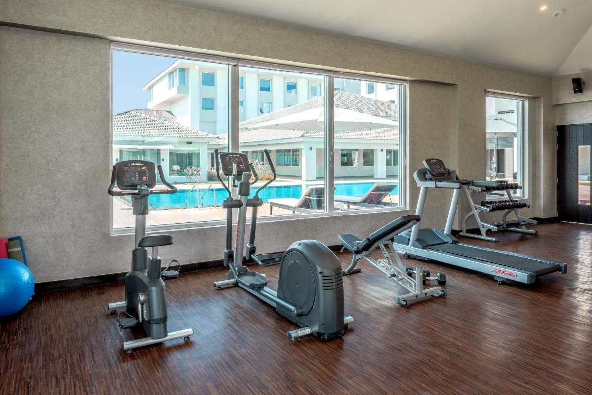 a fitness room with cardio equipment and a swimming pool at The Residency Towers, Rameswaram in Rāmeswaram