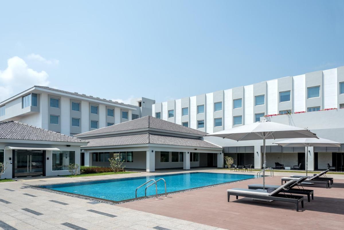 a hotel with a swimming pool in front of a building at The Residency Towers, Rameswaram in Rāmeswaram