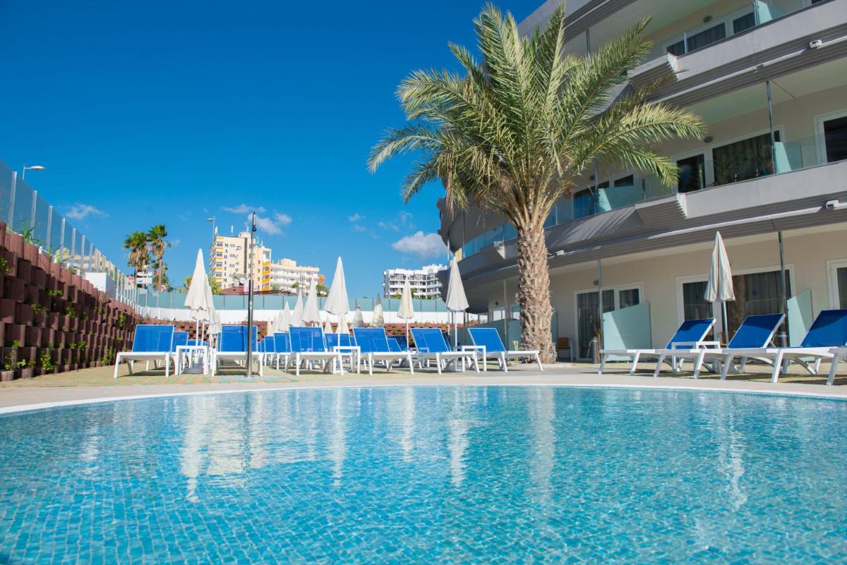 una piscina en un hotel con sillas y sombrillas en HL Suitehotel Playa del Inglés - Adults Only, en Playa del Inglés