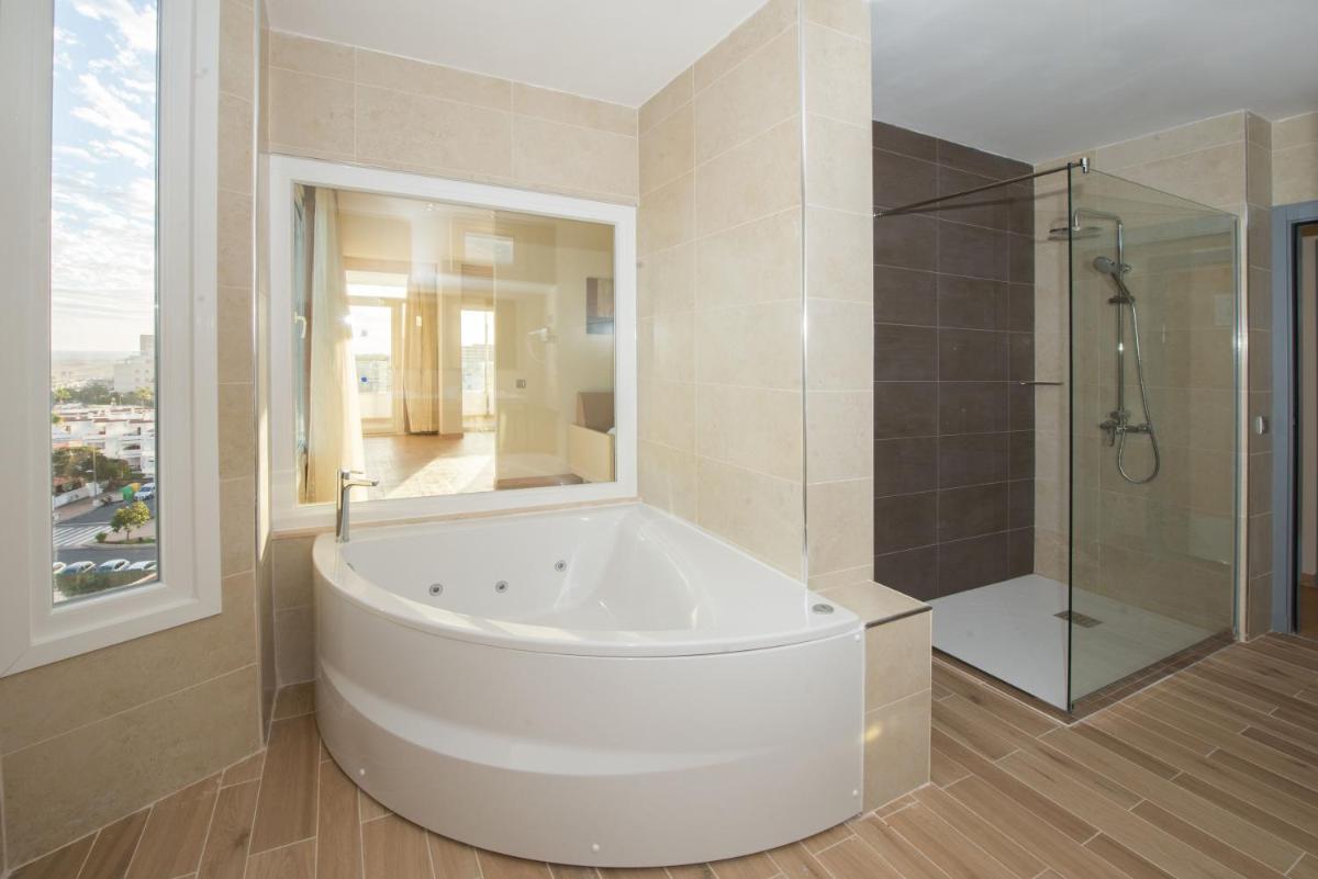 Un baño grande con bañera y ducha. en HL Suitehotel Playa del Inglés - Adults Only, en Playa del Inglés