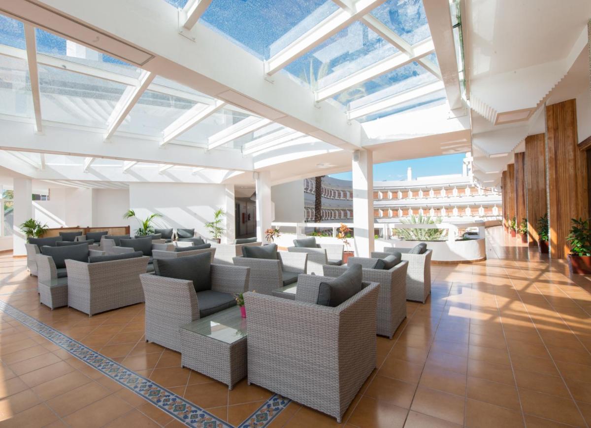Un vestíbulo con sofás, mesas y ventanas. en HL Suitehotel Playa del Inglés - Adults Only, en Playa del Inglés
