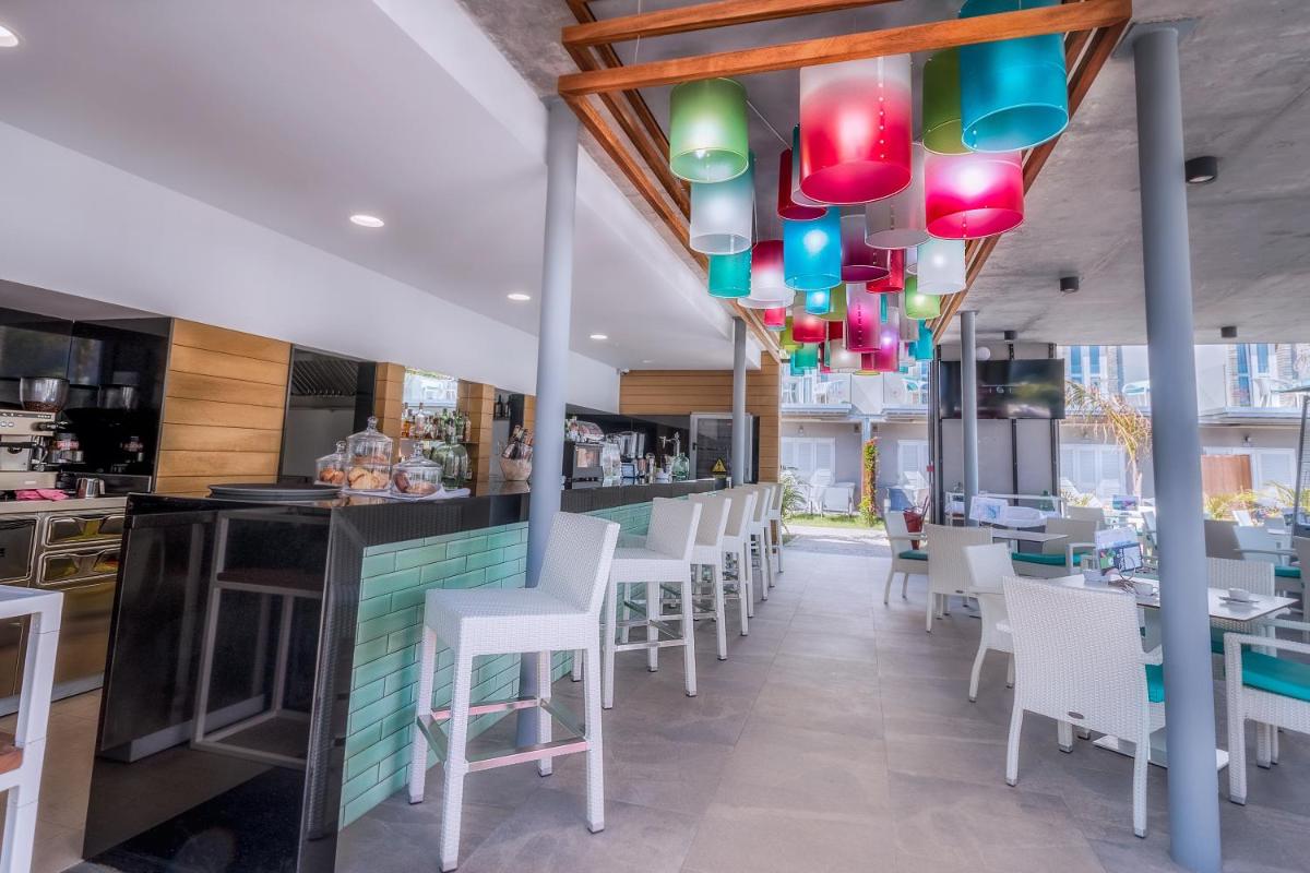 un restaurante con sillas blancas y un bar con luces de colores. en Hotel LIVVO Los Calderones - Adults recommended, en Maspalomas