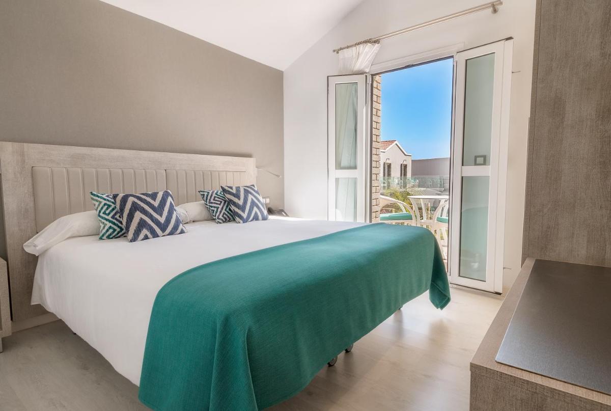 Un dormitorio con una cama grande y una ventana grande. en Hotel LIVVO Los Calderones - Adults recommended, en Maspalomas