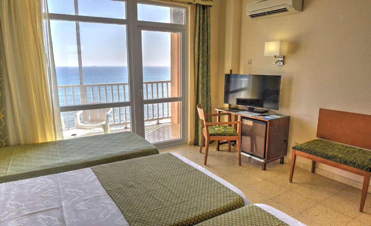 Habitación de hotel con cama, TV y balcón. en Hotel & Spa Entremares, en La Manga del Mar Menor