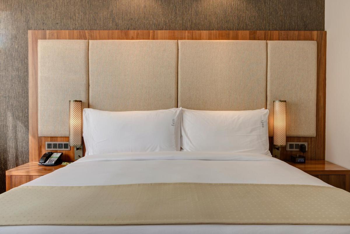 a bedroom with a large white bed with two lamps at Holiday Inn Kolkata Airport by IHG in Kolkata