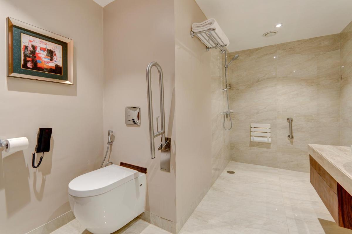 a white bathroom with a toilet and a shower at Holiday Inn Kolkata Airport by IHG in Kolkata