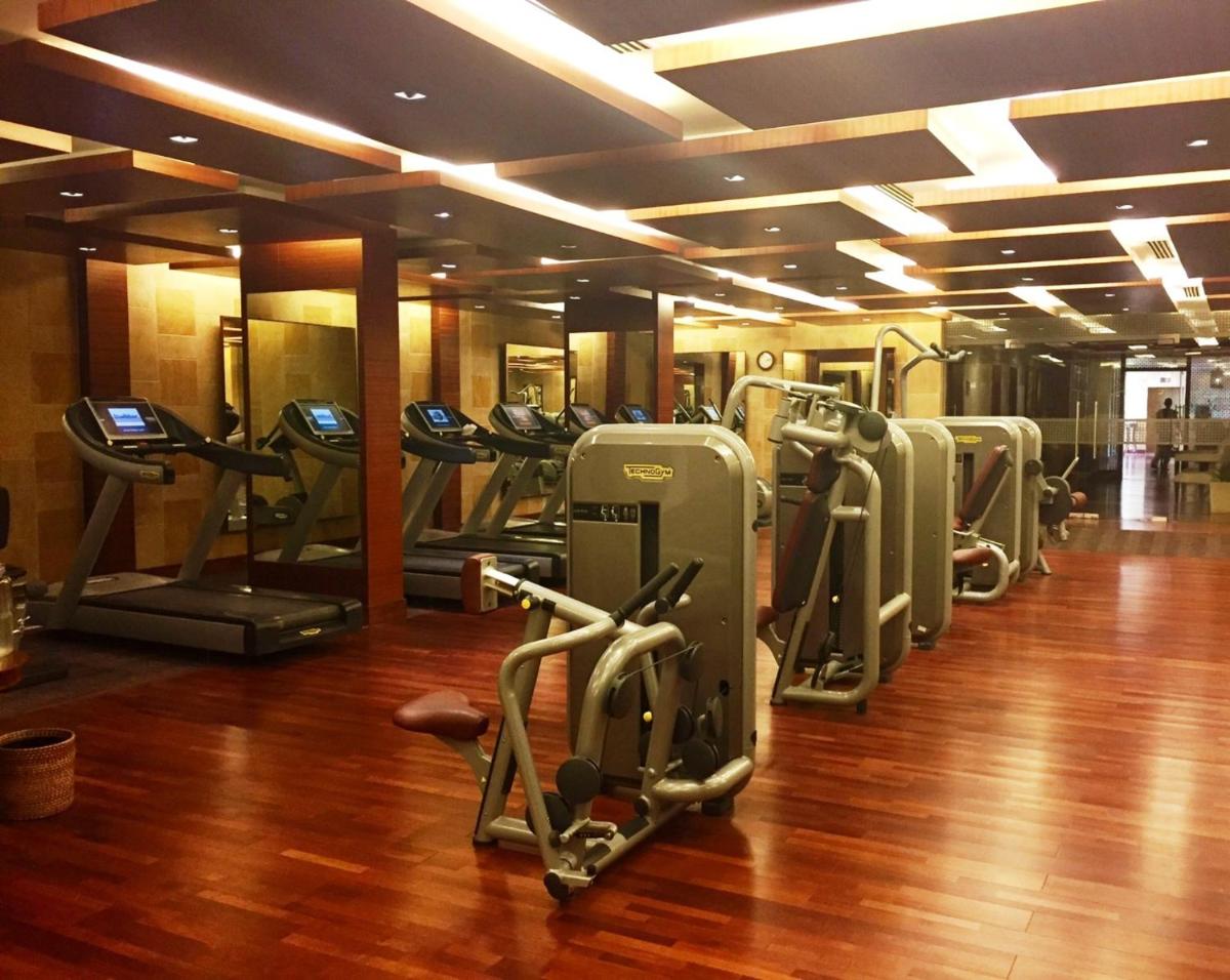 a gym with a row of treadmills and ellipticals at Jaypee Palace Hotel in Agra