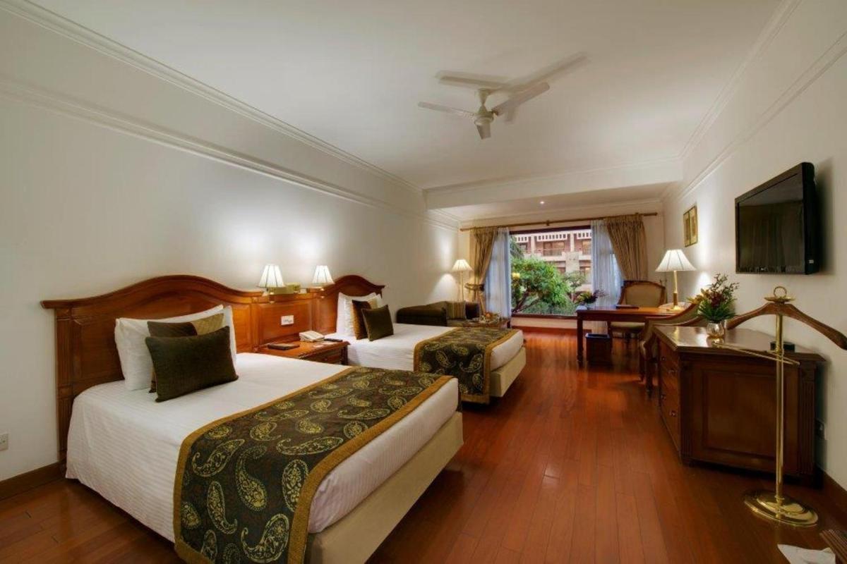 a hotel room with two beds and a desk at Jaypee Palace Hotel in Agra