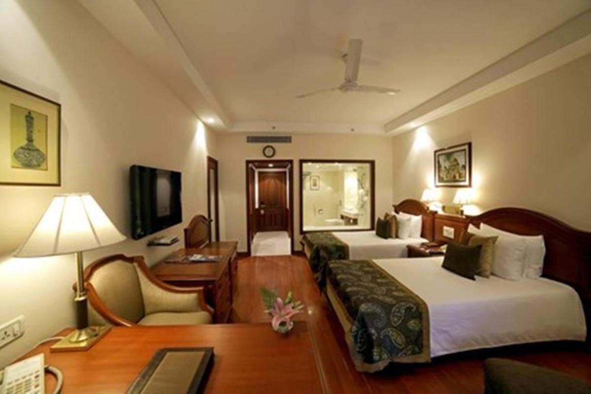 a hotel room with two beds and a desk at Jaypee Palace Hotel in Agra