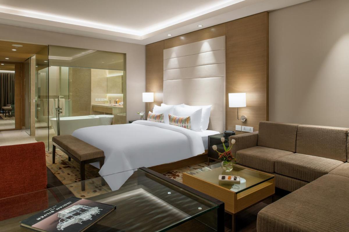 a bedroom with a large bed and a living room at Feathers- A Radha Hotel, Chennai in Chennai