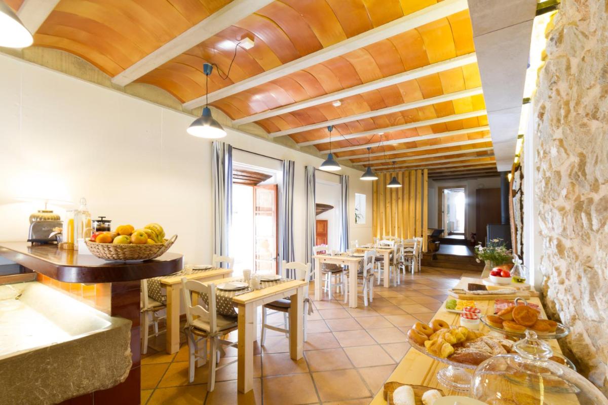 Un restaurante con techos de madera y mesas y sillas. en Can Cota Boutique - Turismo de interior, en Selva