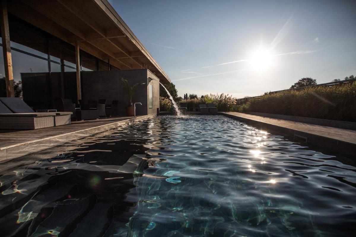 une piscine avec une fontaine en face d'un bâtiment dans l'établissement La Source Des Sens, à Morsbronn-les-Bains