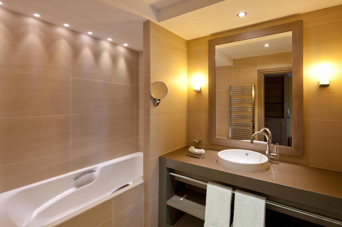 une salle de bain avec un lavabo, un miroir et une baignoire dans l'établissement Hôtel Le Nouveau Monde, à Saint-Malo