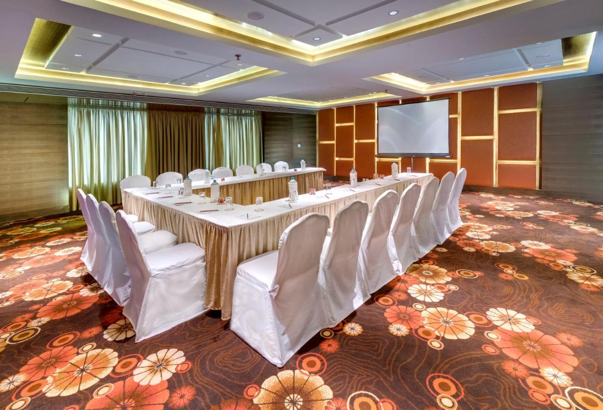 a conference room with a long table and chairs and a screen at Pride Plaza Hotel, Kolkata in Kolkata