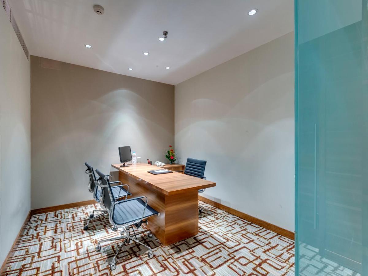 an office with a wooden desk and chairs at Pride Plaza Hotel, Kolkata in Kolkata