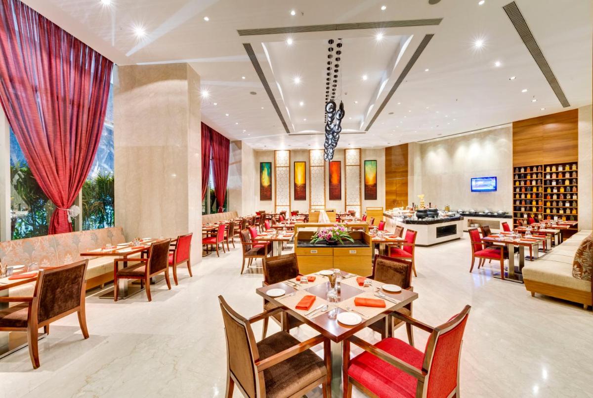 a restaurant with tables and chairs and a couch at Pride Plaza Hotel, Kolkata in Kolkata