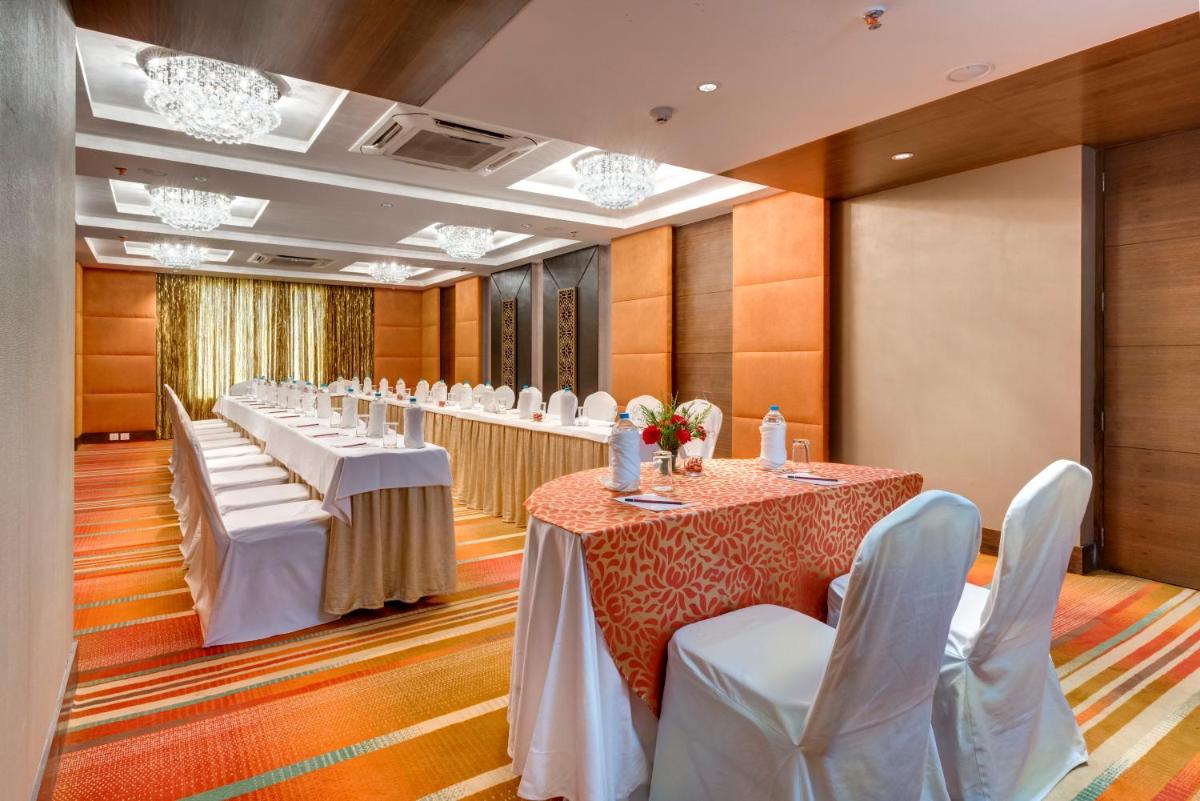 a row of tables in a room with white chairs at Pride Plaza Hotel, Kolkata in Kolkata