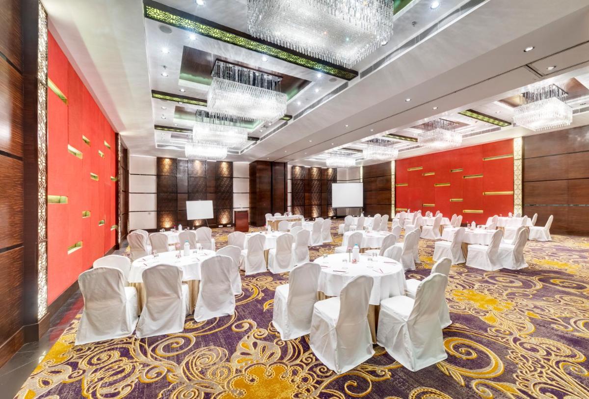 a banquet hall with white tables and white chairs at Pride Plaza Hotel, Kolkata in Kolkata