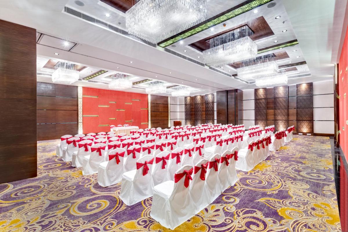 a large banquet hall with white tables and red chairs at Pride Plaza Hotel, Kolkata in Kolkata