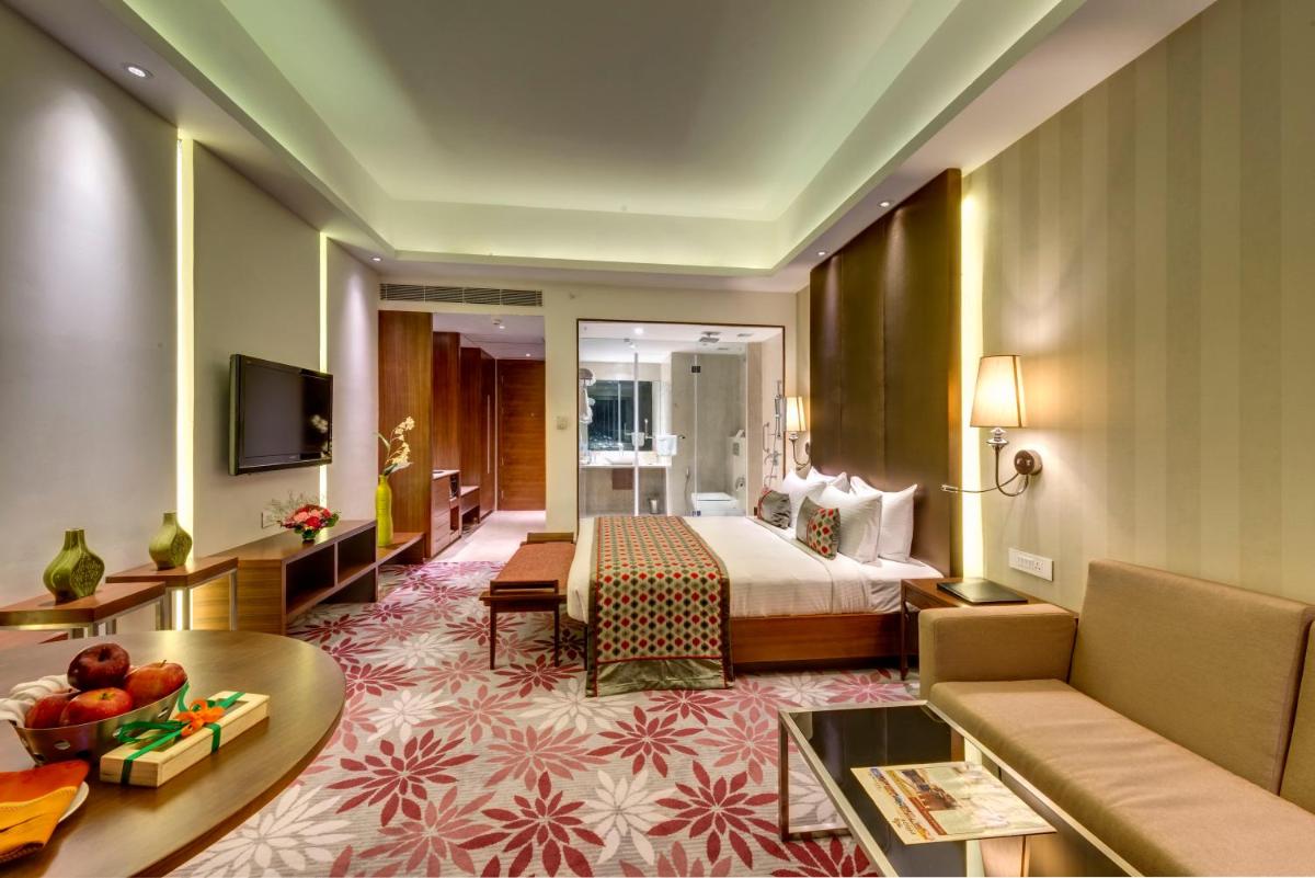 a hotel room with a bed and a living room at Pride Plaza Hotel, Kolkata in Kolkata