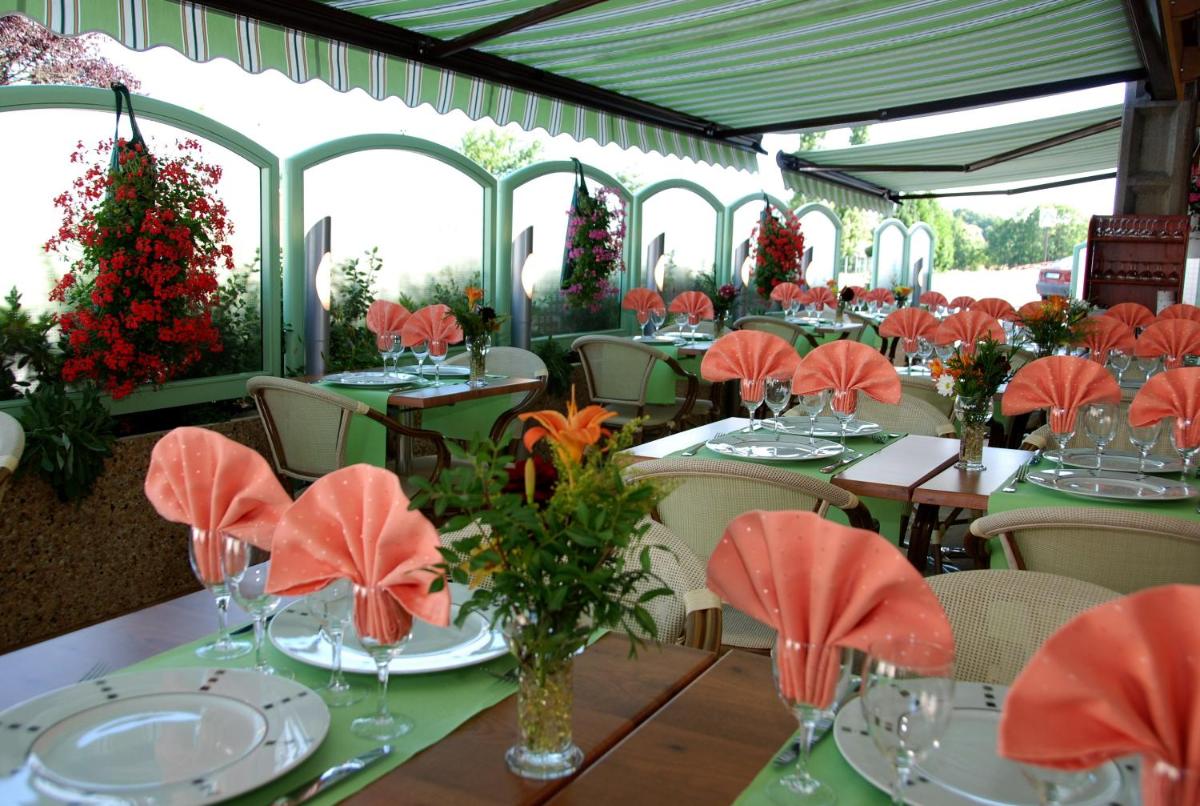 un restaurant avec des tables et des chaises avec des fleurs dessus dans l'établissement Logis Hôtel Bellevue, à Bessines-sur-Gartempe