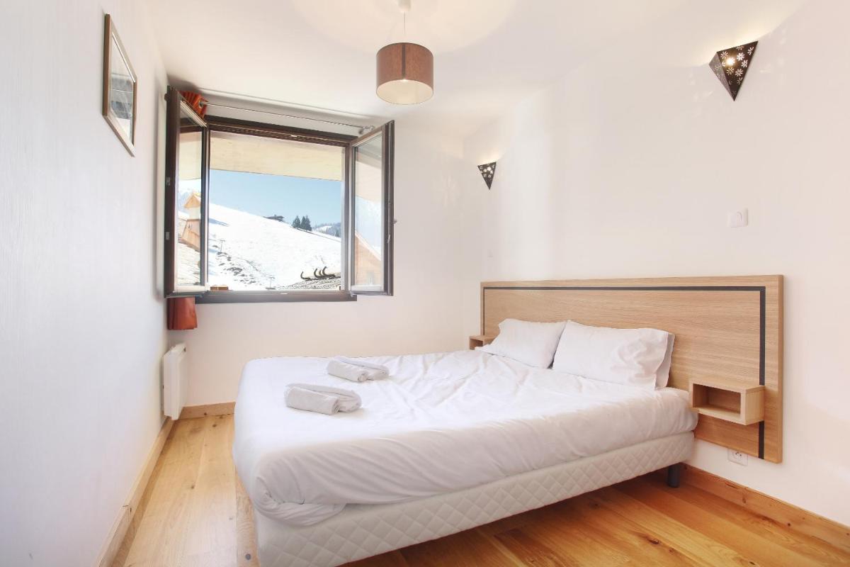 une chambre avec un grand lit blanc avec une fenêtre dans l'établissement Résidence Odalys Mendi Alde, à La Clusaz