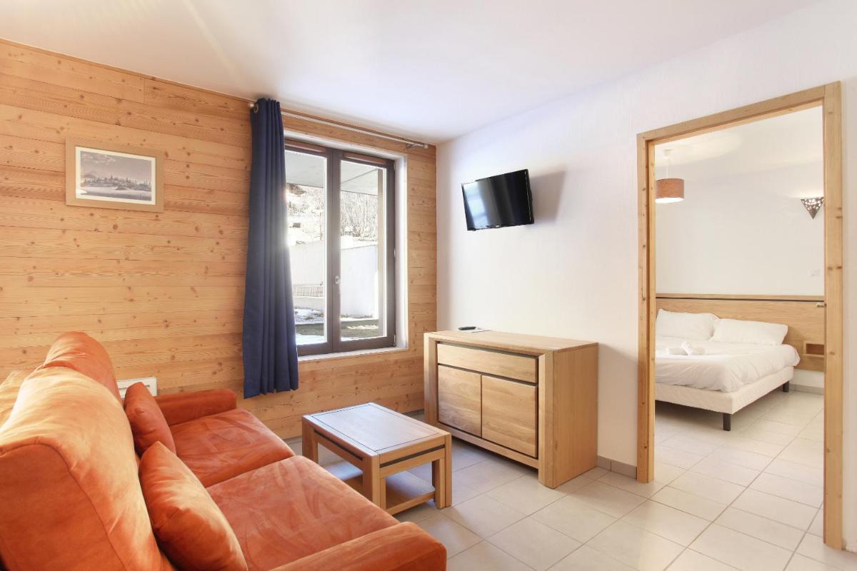un salon avec un canapé et un lit dans l'établissement Résidence Odalys Mendi Alde, à La Clusaz
