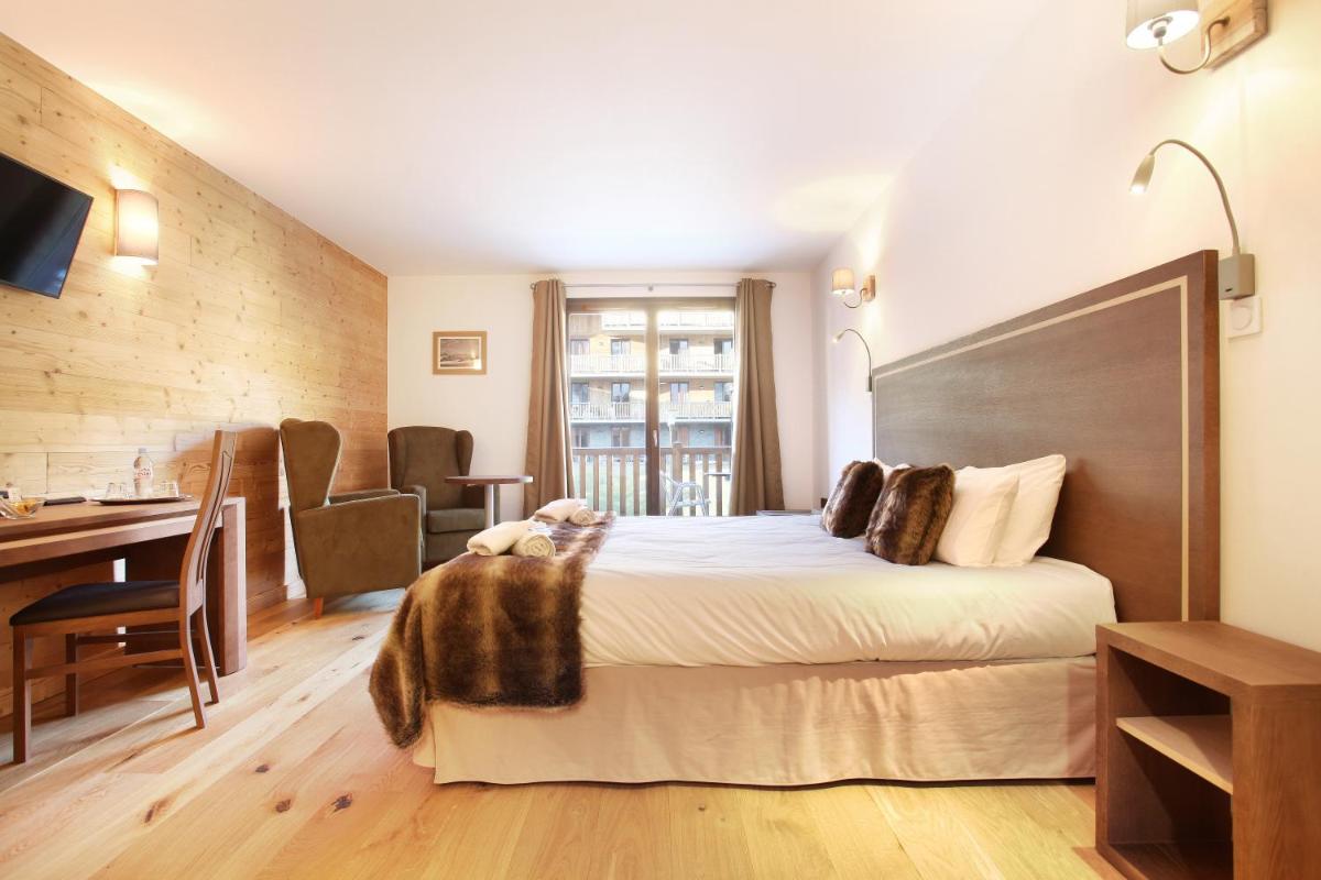 une chambre d'hôtel avec un grand lit et un bureau dans l'établissement Hôtel Odalys Le Chamois, à La Clusaz