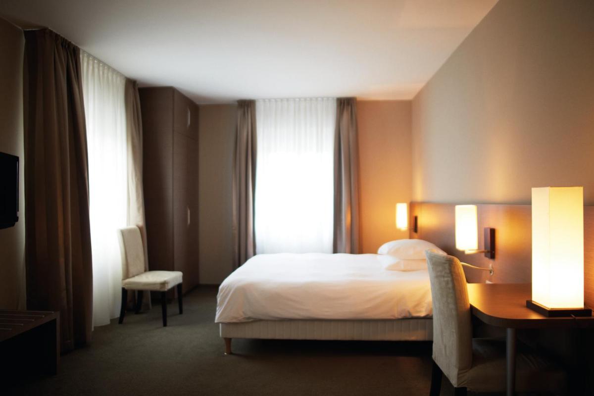 une chambre d'hôtel avec un lit, un bureau et une fenêtre dans l'établissement La Source Des Sens, à Morsbronn-les-Bains