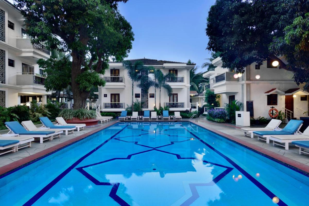 a swimming pool in front of a building with lounge chairs at Radisson Goa Candolim in Candolim